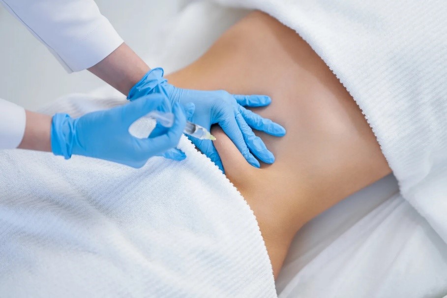 Een arts met blauwe handschoenen zet een injectie met een lokaal anestheticum in de onderrug van een patiënt.